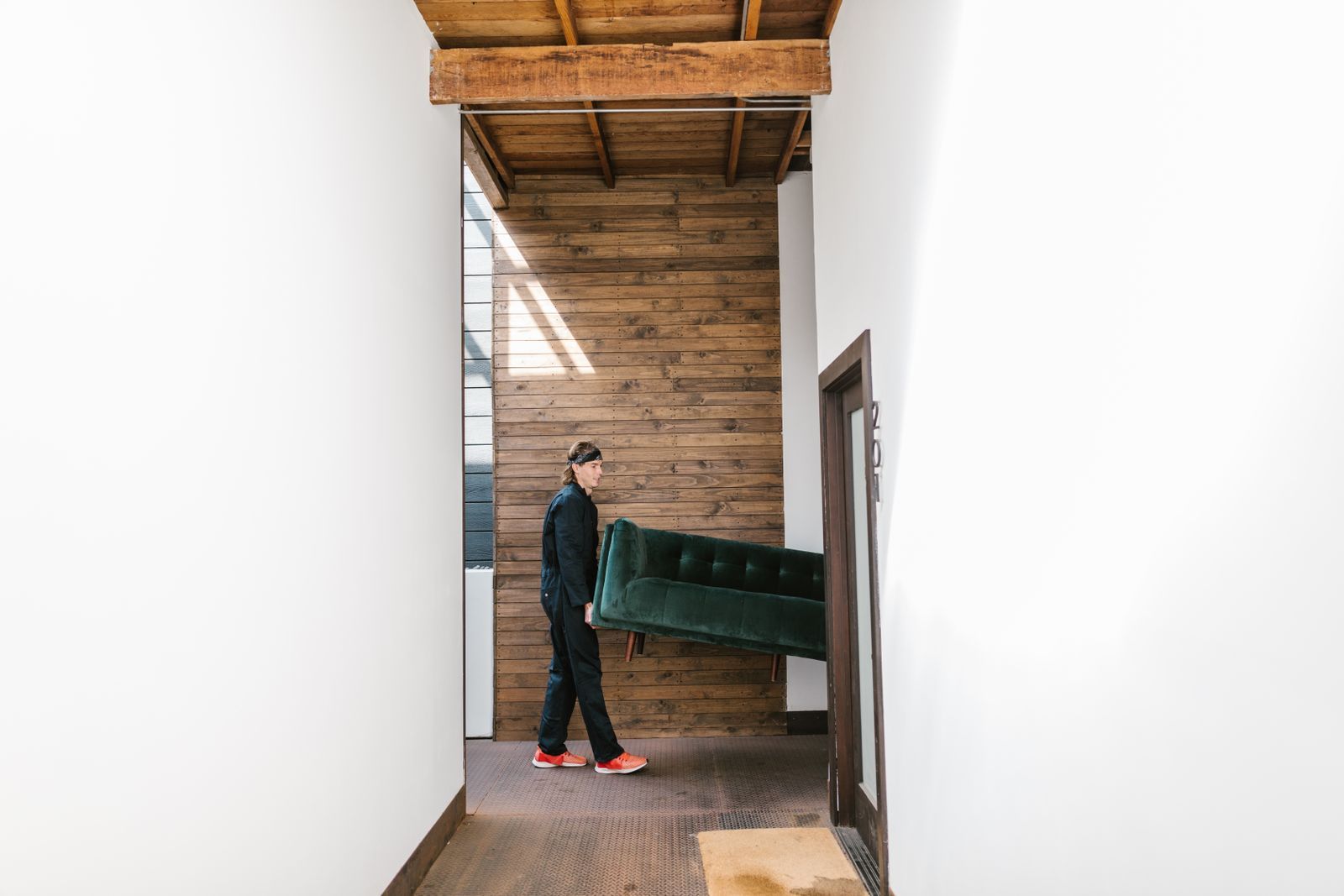 A mover carrying a sofa down a hallway during a clear-out