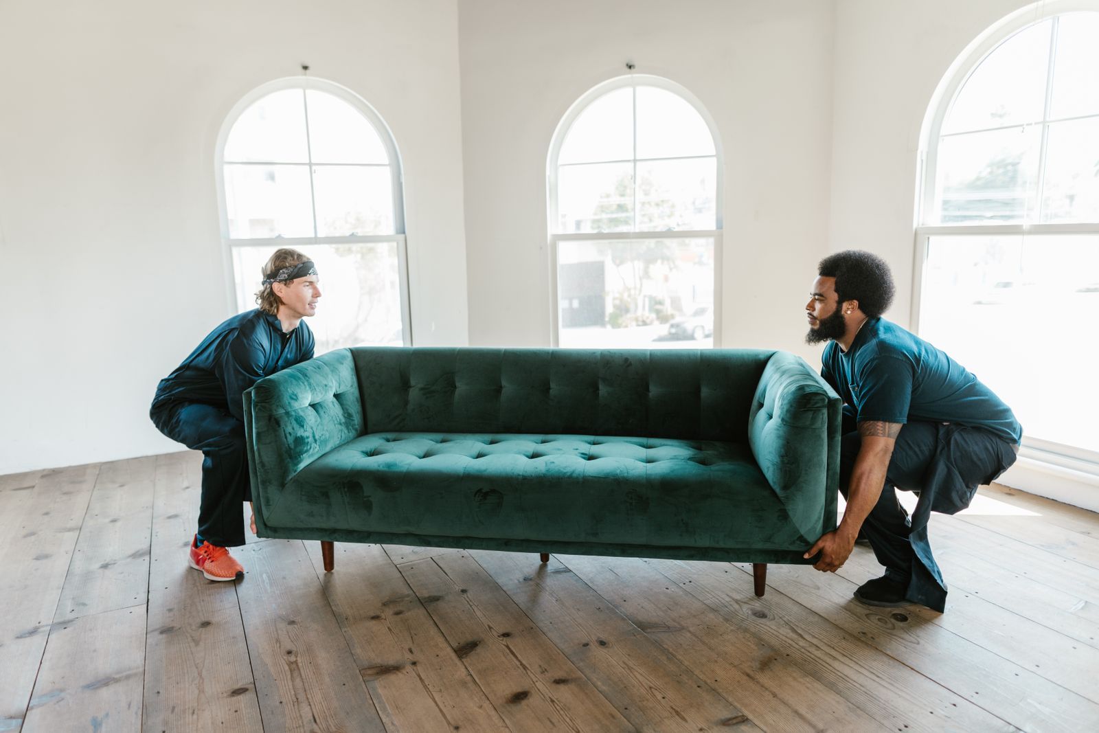 Two movers carrying a sofa out of a room