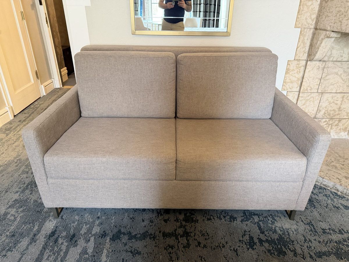Grey loveseat in a hotel room, from a hotel furniture liquidation